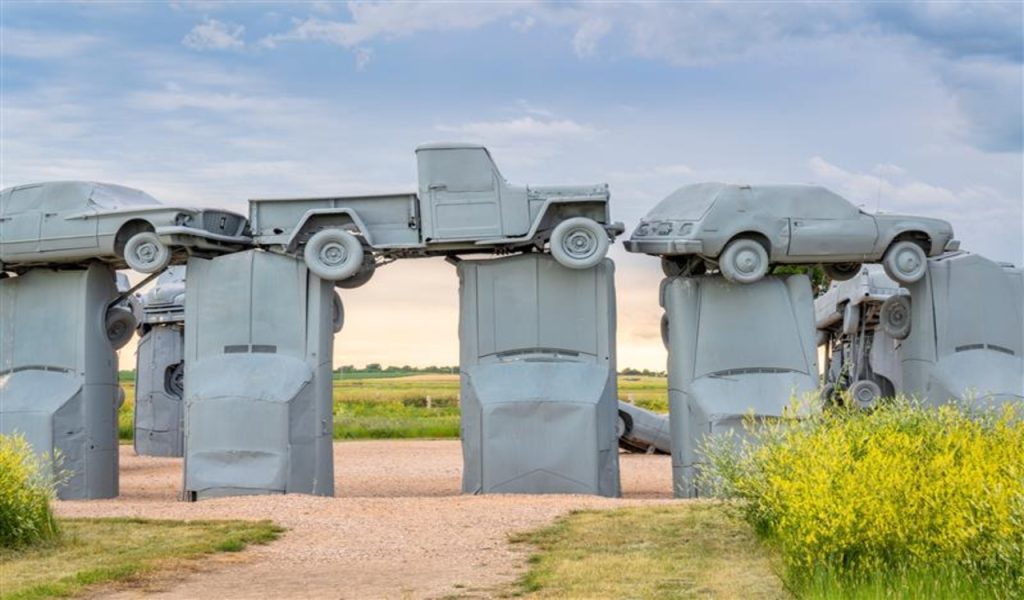 Carhenge - famous car sculpture created by Jim Reinders, a modern replica of England's Stonehenge using old cars, a summer scenery with a field of yellow sweet clover in front.