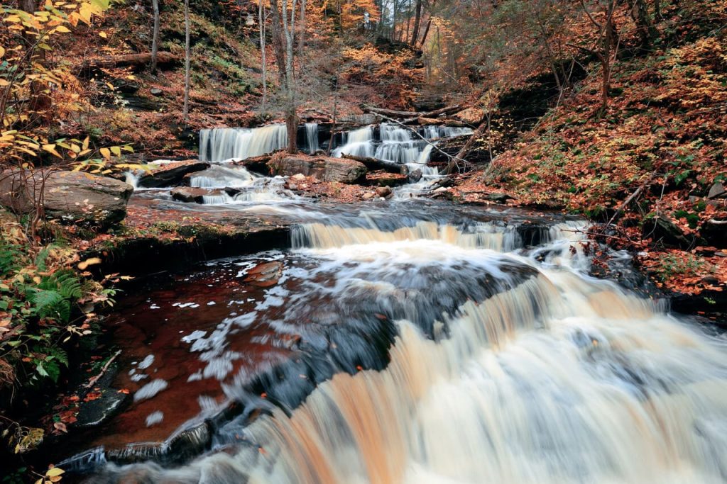 Autumn waterfalls in park with colorful foliage.