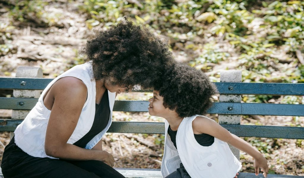 A Woman Playing with her Daughter on a Park Bench
