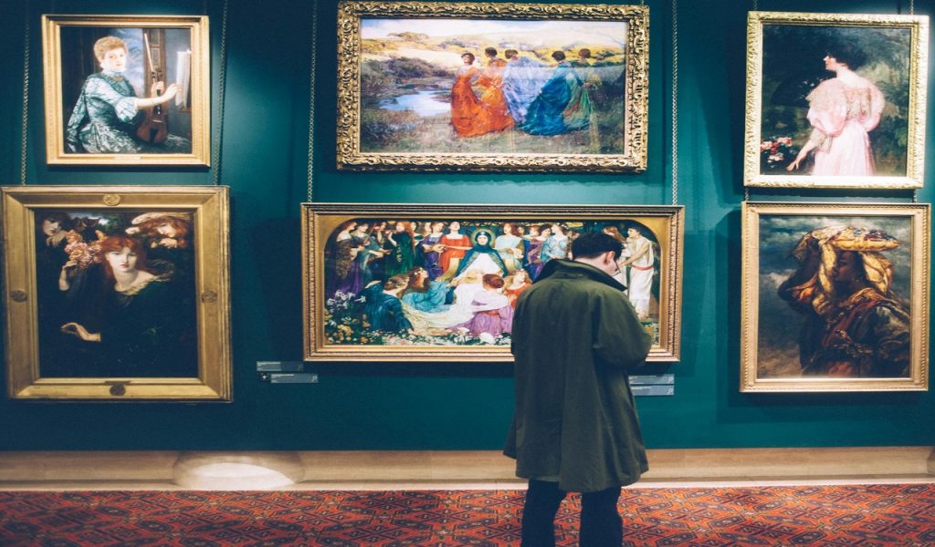 Man Standing in Front of Paintings
