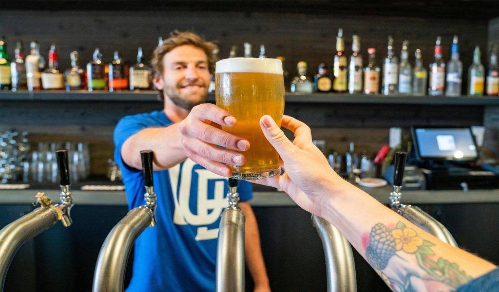 11 U.S. Cities Beer Lovers Should Put on the Map – Her Life Adventures Man Handing a Person a Glass of Beer