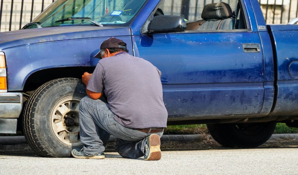 Man Repairing Tire of Blue Truck in Houston
