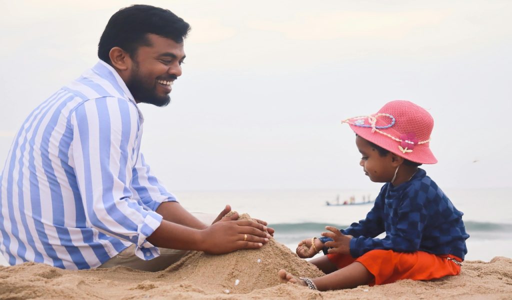 Father and Child Playing on the Beach Sand 