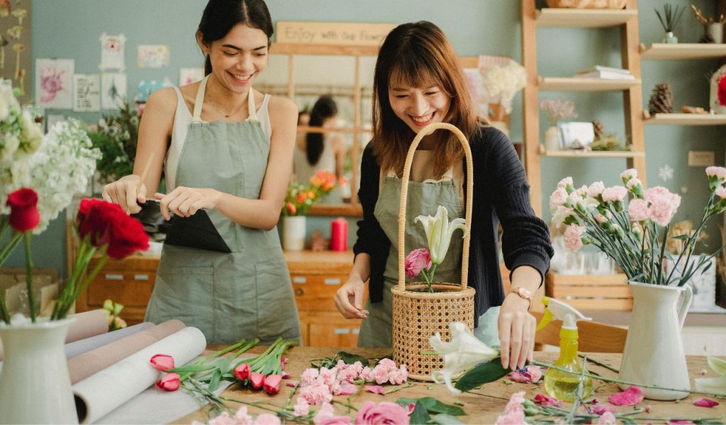 Cheerful florists working in floristry store in daytime 