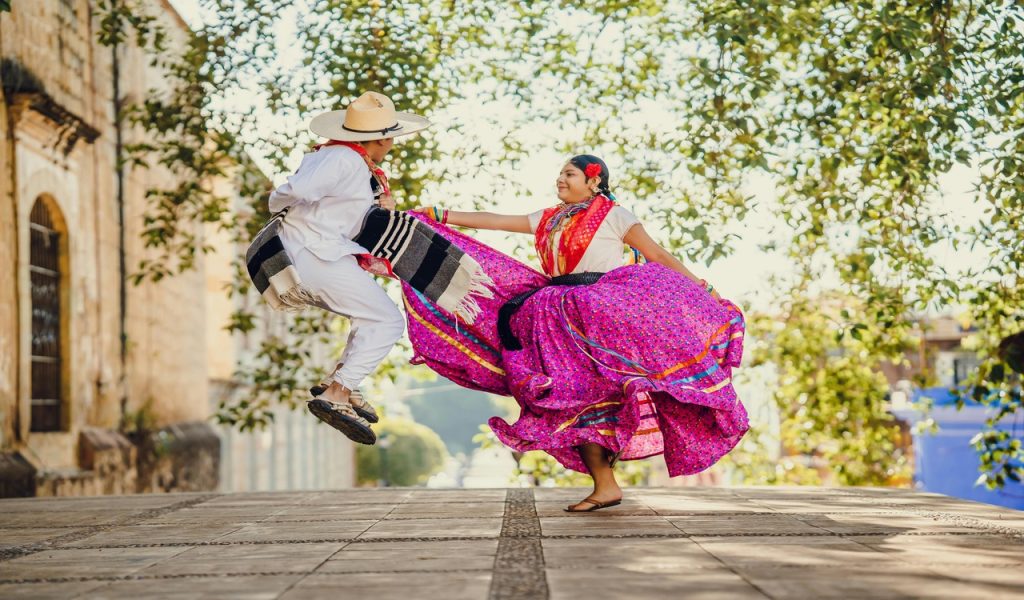 People Dancing on City Street Wearing Traditional Clothing
