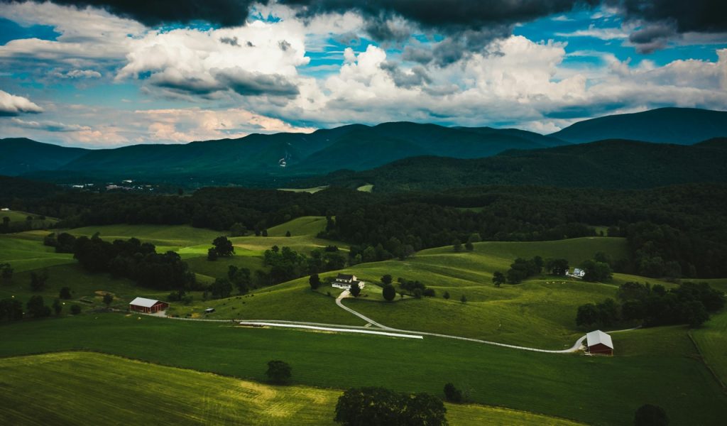 Bâtiments sur des collines verdoyantes derrière les montagnes sous un ciel nuageux