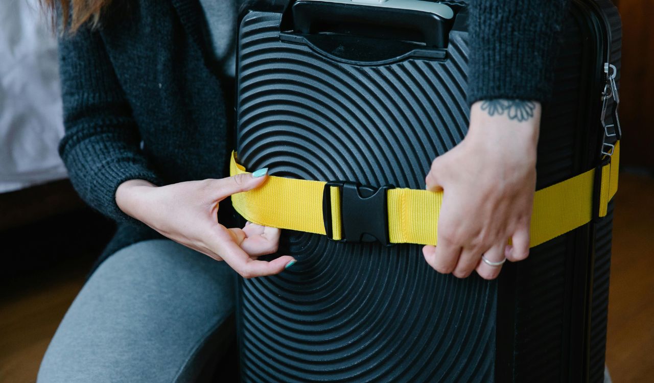 A Person Checking the Strap on Luggage