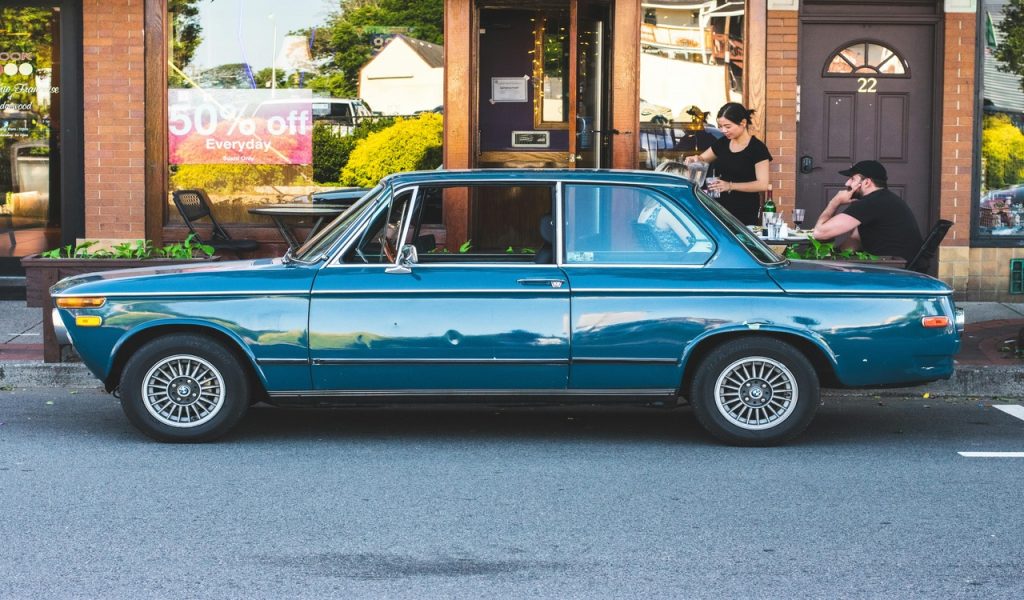 Blue Car Parked in Front of a Shop 