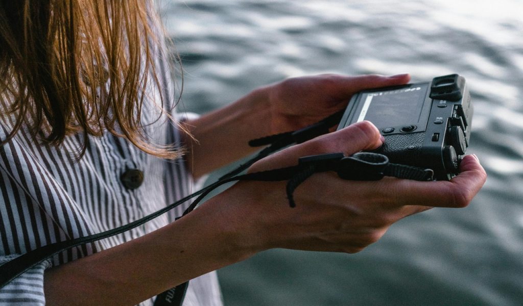 Close-up Photo of Woman Viewing Photos from Her Camera Near Body of Water