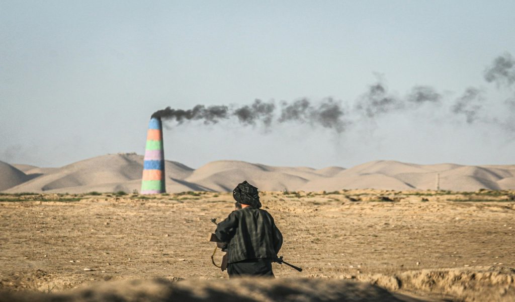 Man Observing Factory Smoke in Afghan Desert