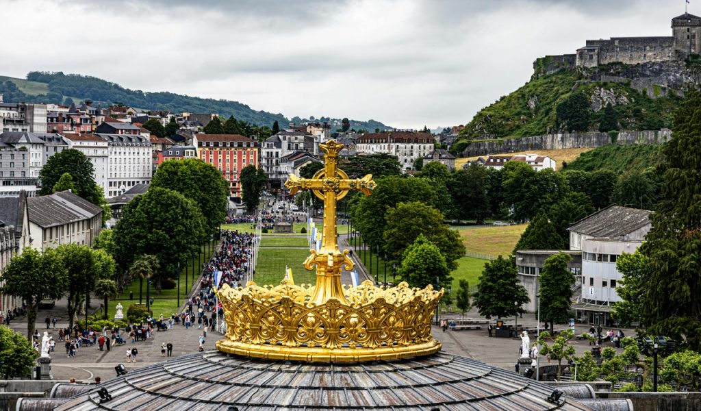 Golden Cross Overlooking Lourdes Cityscape
