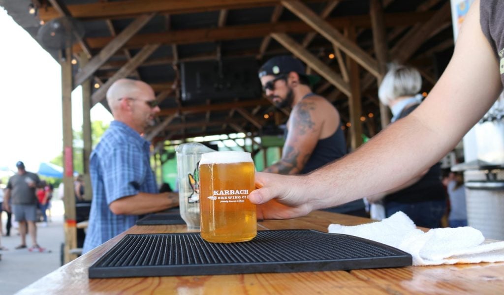 11 U.S. Cities Beer Lovers Should Put on the Map – Her Life Adventures Man Holding Glass With Yellow Liquid on Black Tray