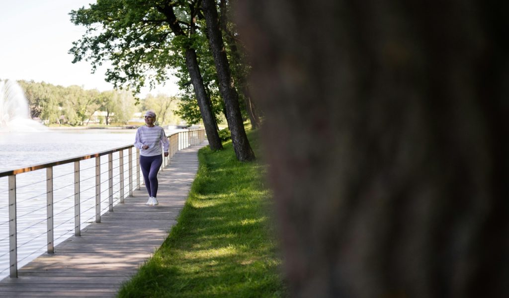 Photograph of an Elderly Woman Jogging Near Trees 
