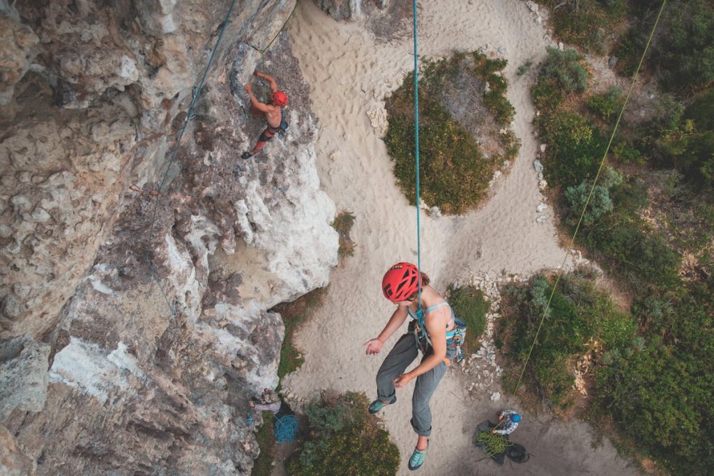 People in helmets with ropes climbing on rocky mountains