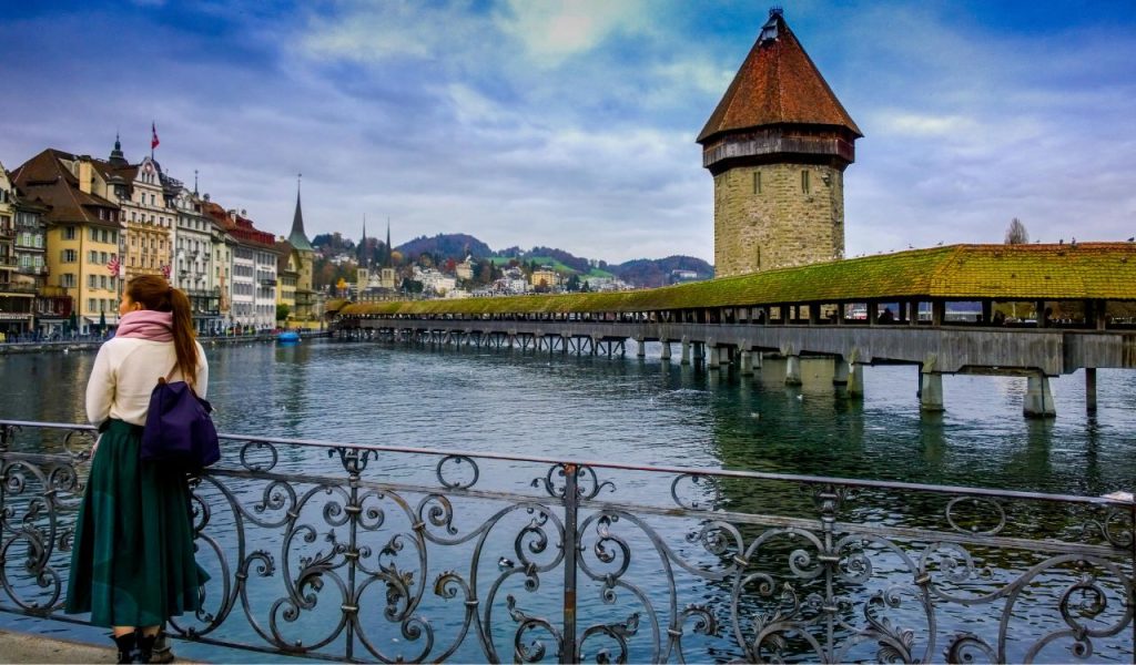 Woman Standing Against Handrails Beside Body of Water
