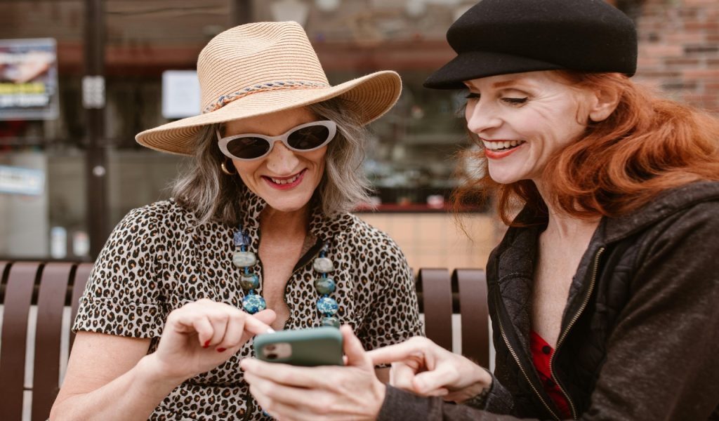A Pair of Women Wearing Hats Looking at a Mobile Phone
