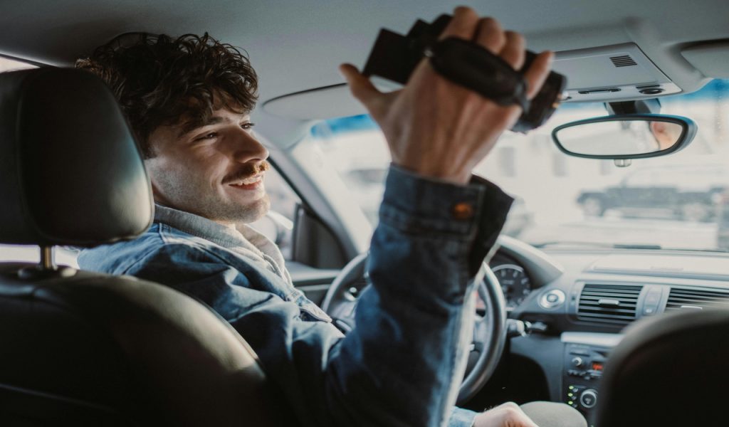 A Man Sitting in a Car Holding a Camcorder
