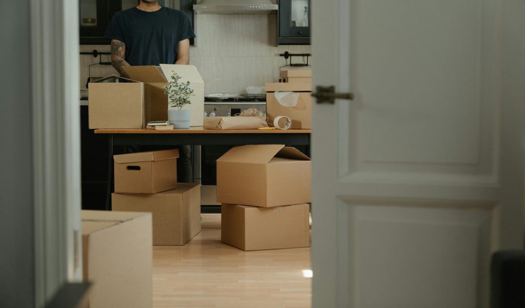 Man in Black Shirt Standing Near Brown Cardboard Boxes
