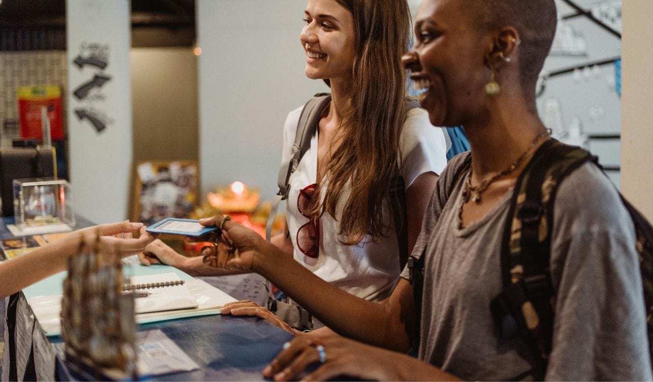 Women Receiving a Hotel Room Card at the Reception Desk