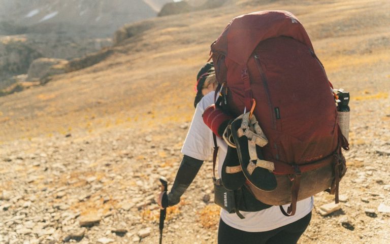 A Man Carrying a Backpack in Mountains