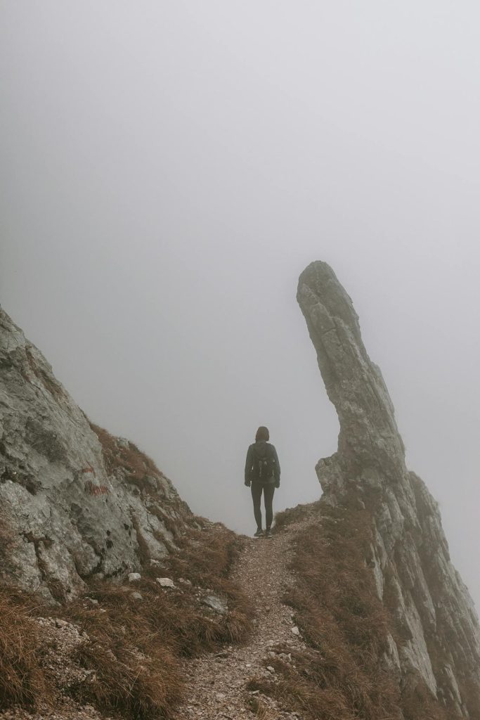 Hiker stopping on a misty path, trusting instincts before continuing.