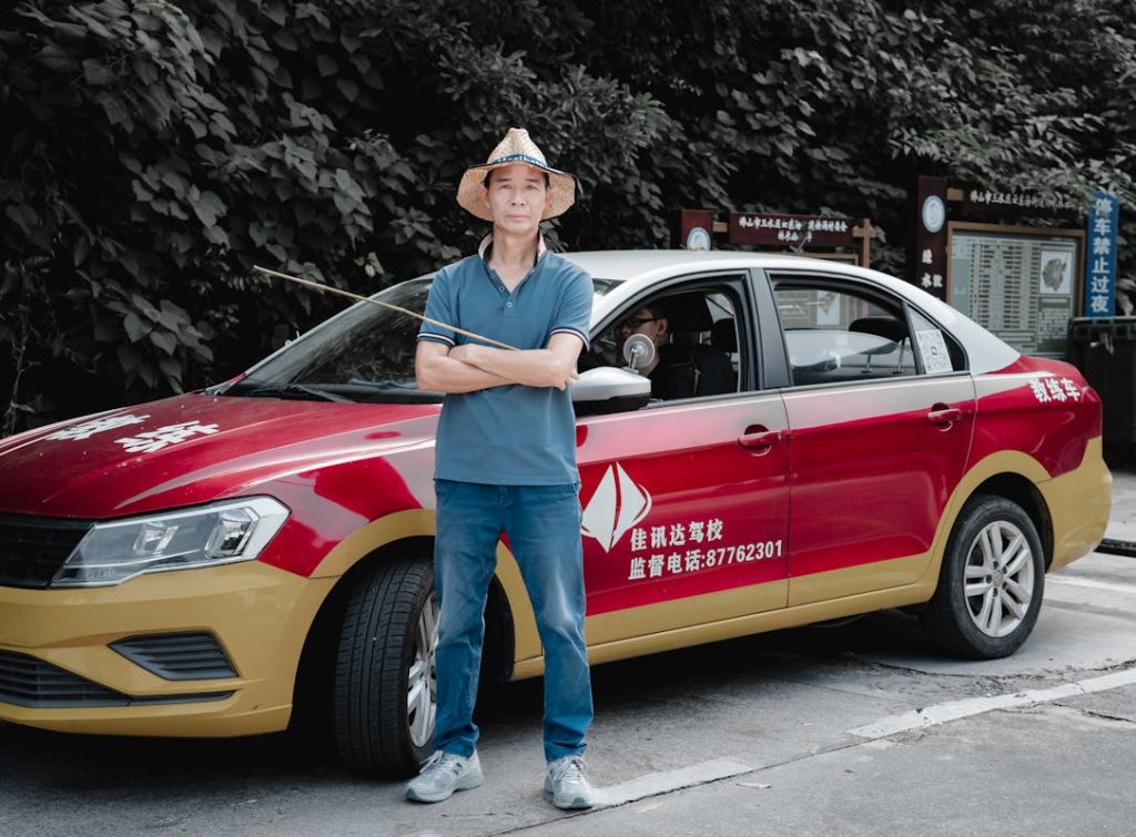an Standing Beside Red Taxi with Straw Hat