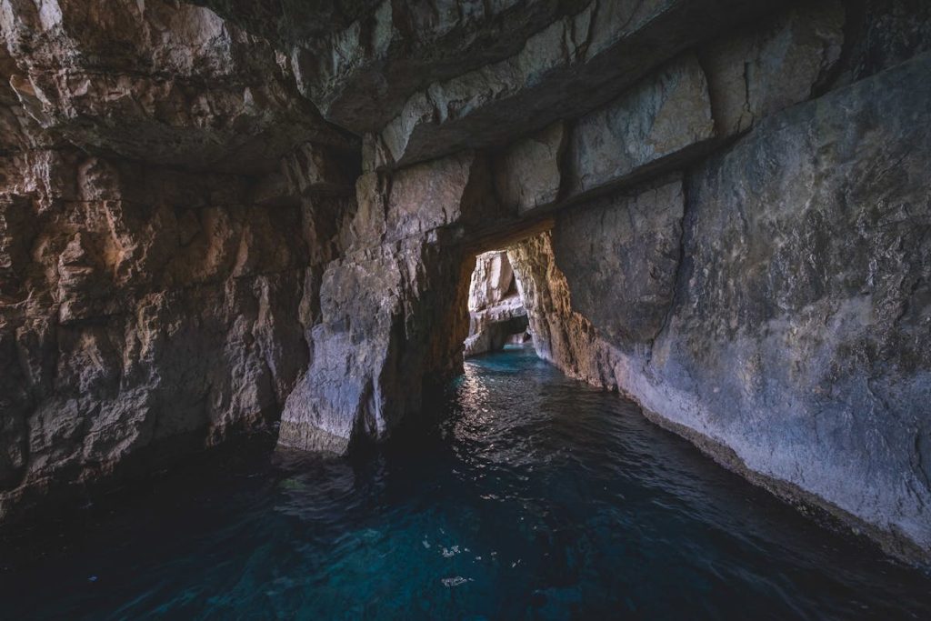 A cave with blue water and rocks