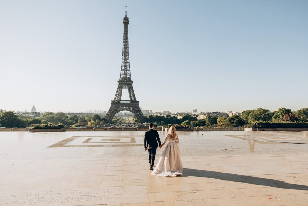 10 Countries With Rising Trip Costs And How To Budget For Them – Her Life Adventures Woman and Man Walking in Park in Front of Eiffel Tower