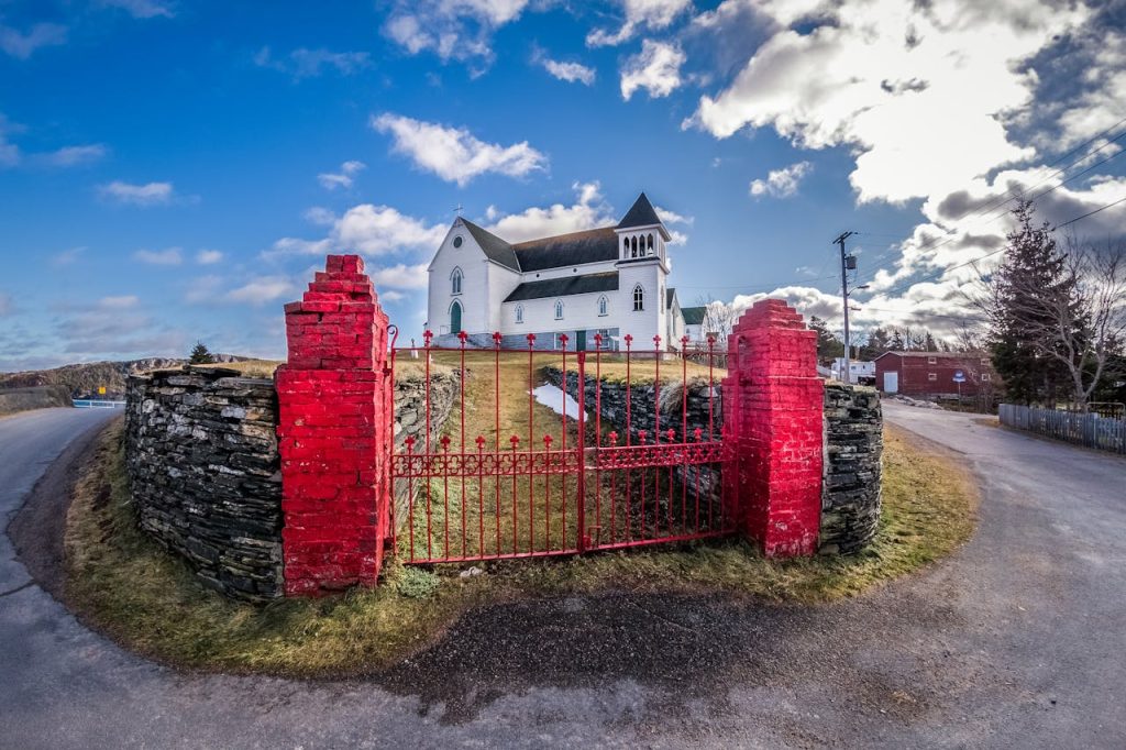 Gate against church facade under cloudy sky in countryside