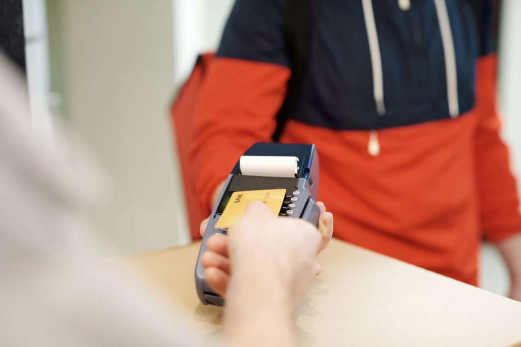 A traveler paying via phone or tapping a card at a small shop.
