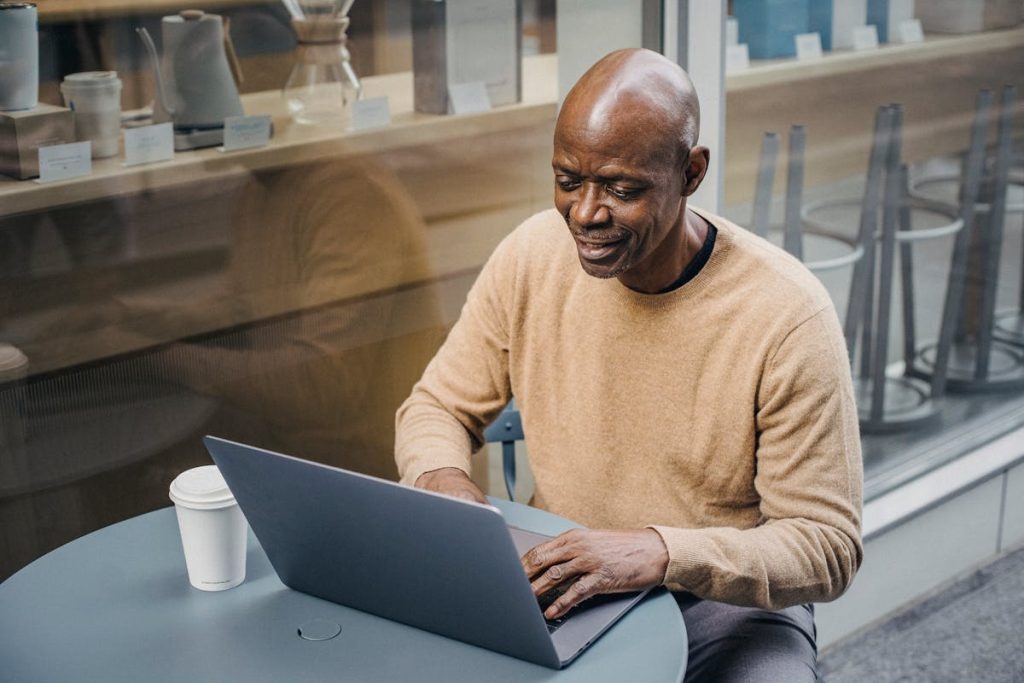 mart mature black man typing on netbook in outdoor cafe