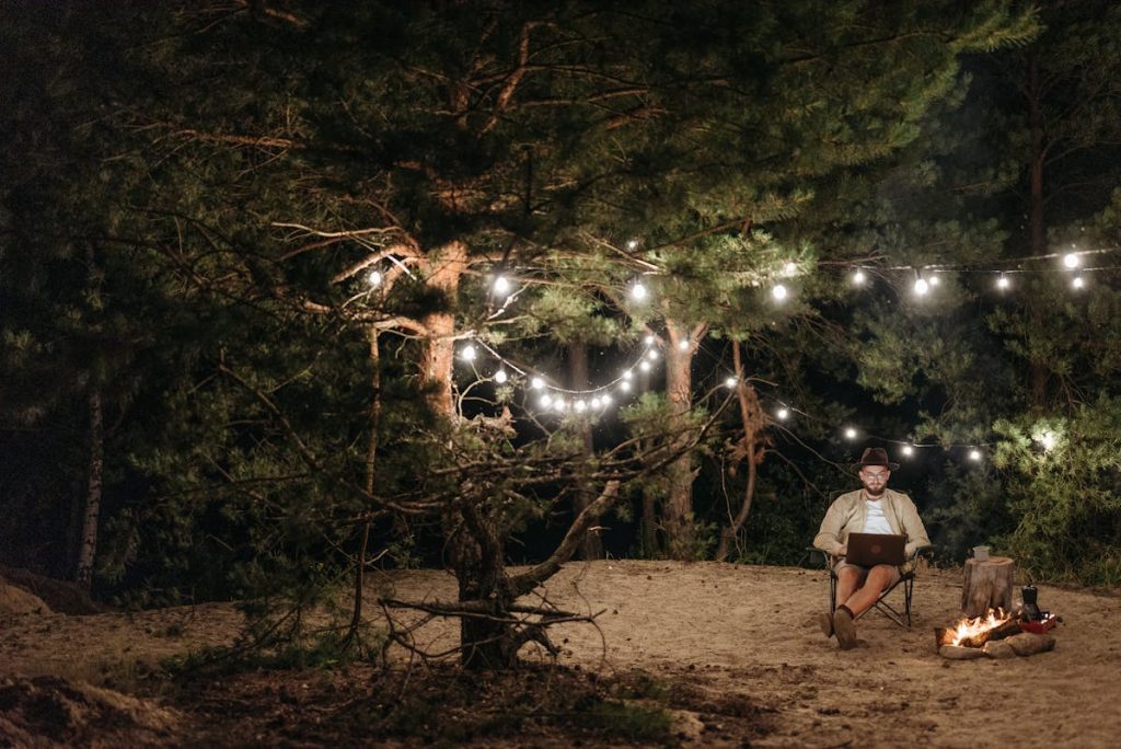 A Man Working Near the Bonfire Under the Green Trees at Night
