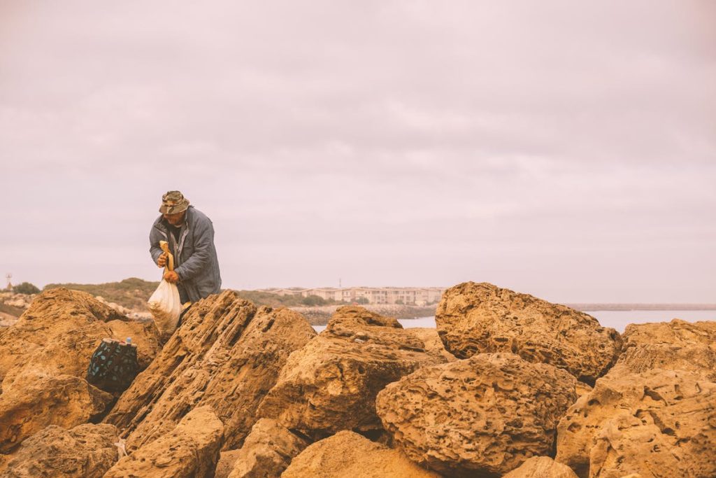 Man Collecting Seashells on a Rocky Shoreline
