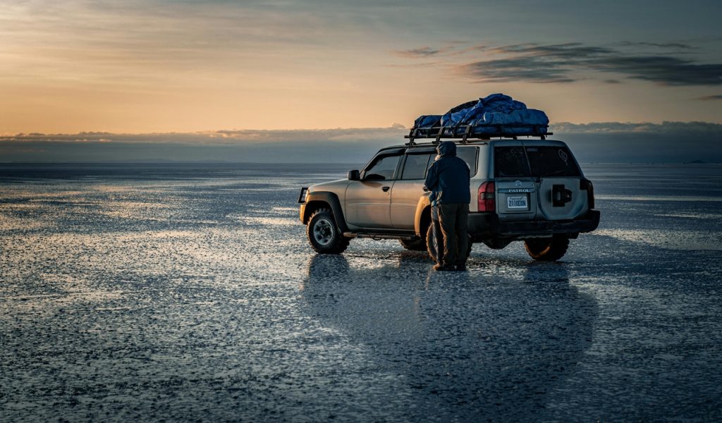 Couple Standing by a Jeep in Wet Flat Landscape
