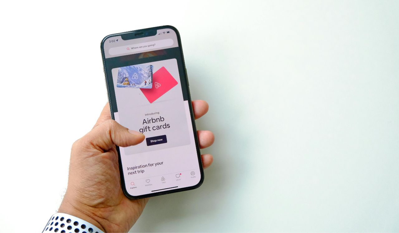 Close-up of a Man Holding a Smartphone Displaying a Shop with Airbnb Gift Cards