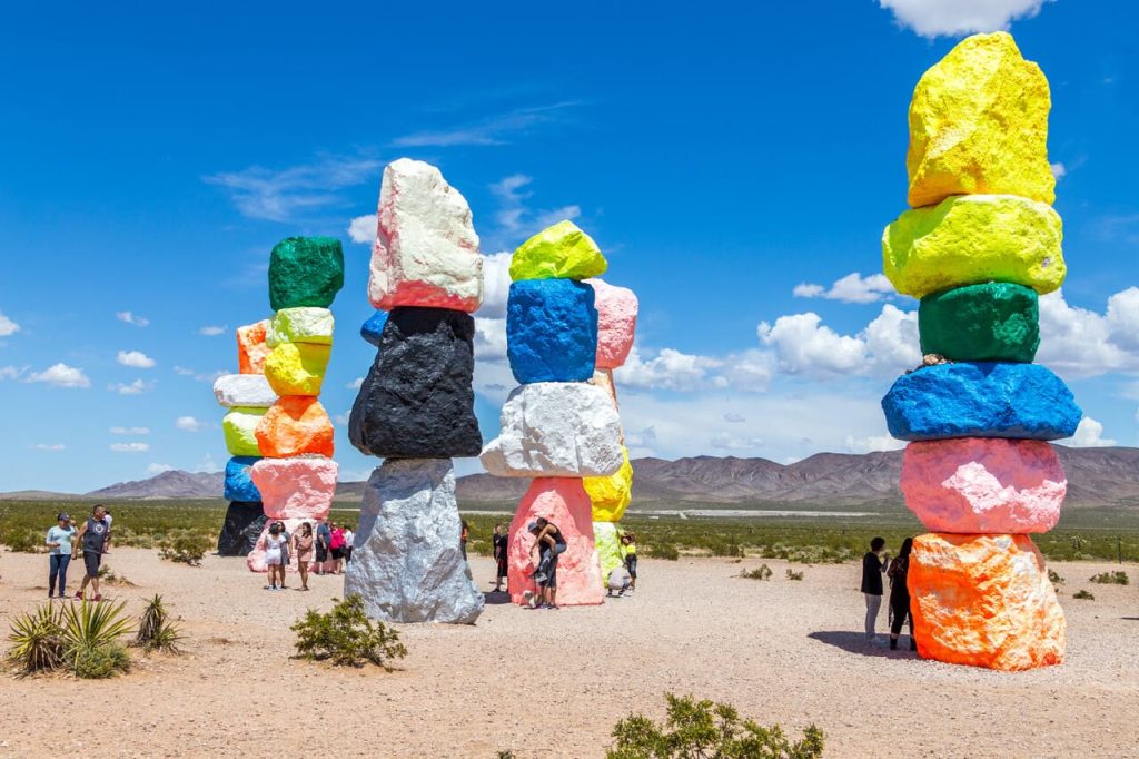 Seven Magic Mountains art installation near Las Vegas city. Pillars made of neon colored boulders stand against barren desert background and blue sky.