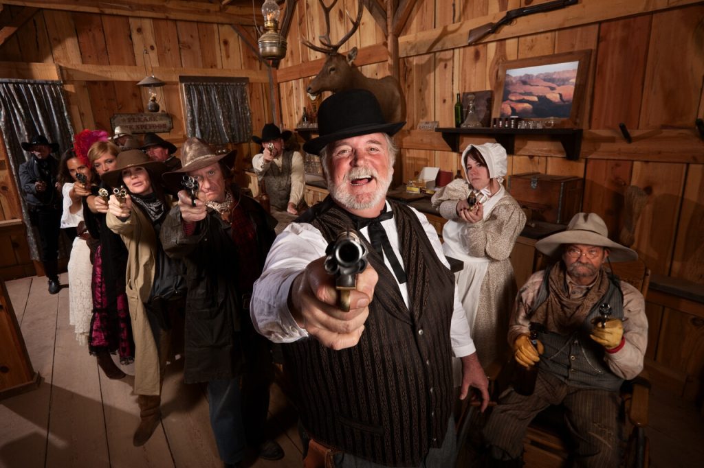 Laughing man with old west gang point guns in a saloon