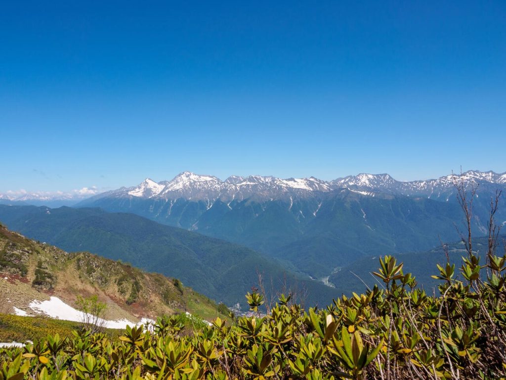 Epic mountain ranges twisting under the sun, with vibrant slopes and cloud shadows, embody the strength and beauty of nature.