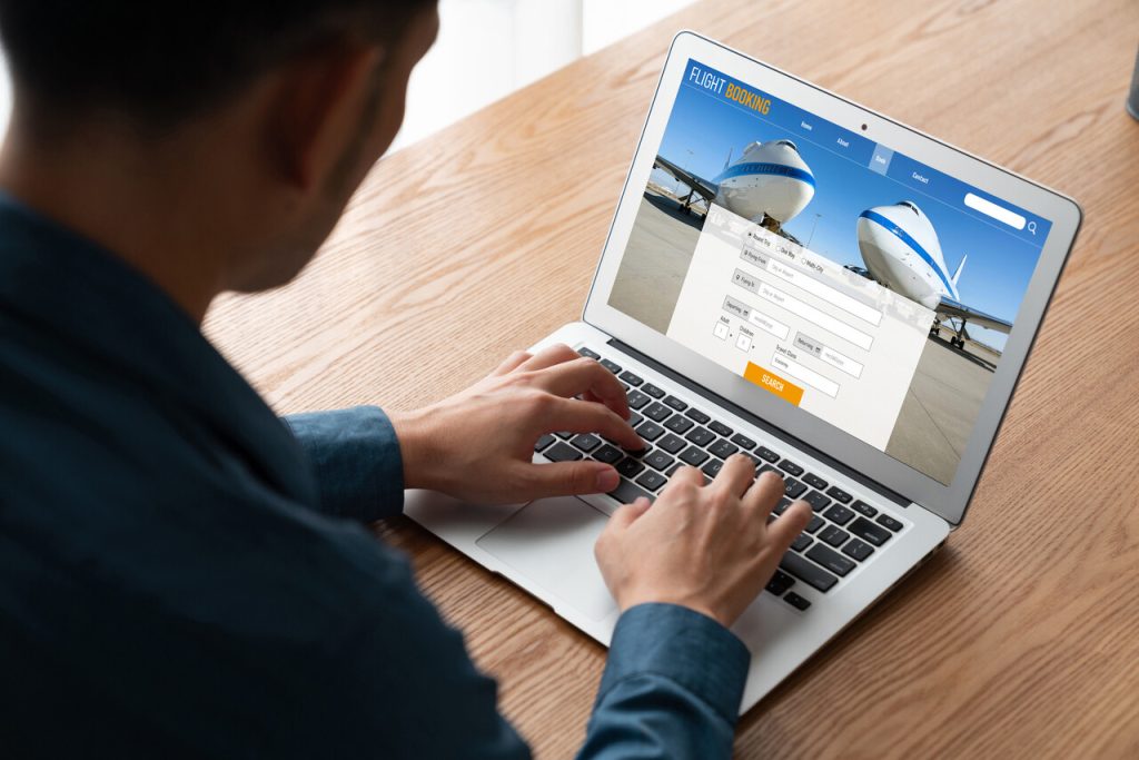 A person booking a flight or hotel on a verified travel website with clear security icons visible on the screen.