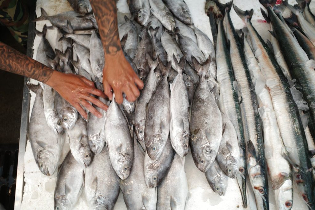 hands selecting fresh seafood at a busy market stall,