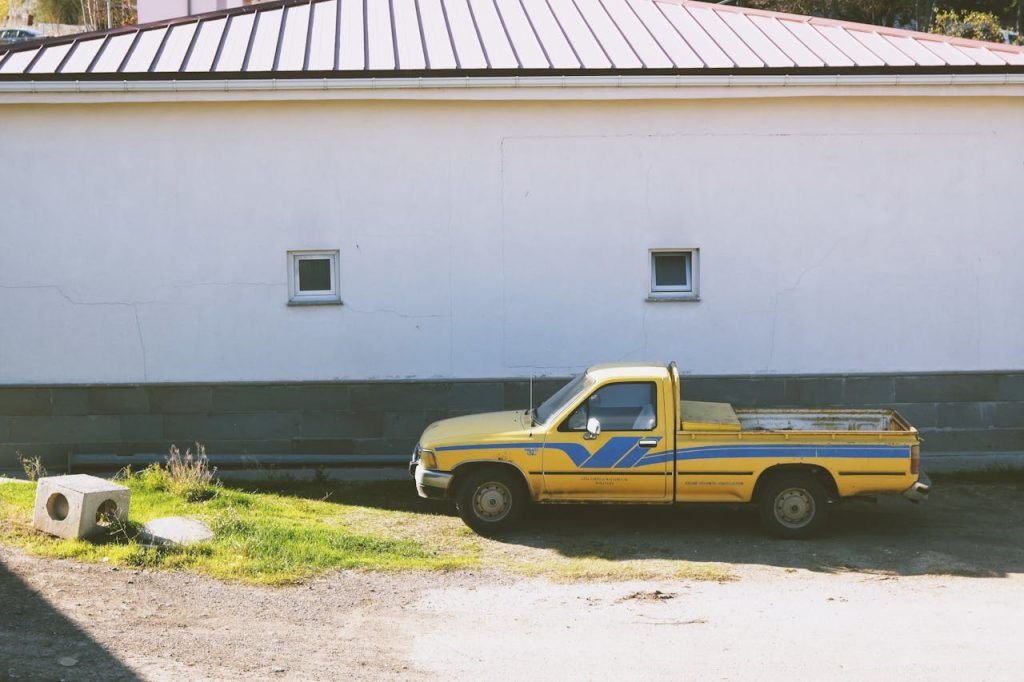 Vintage Yellow Truck Parked by White Wall Outdoors