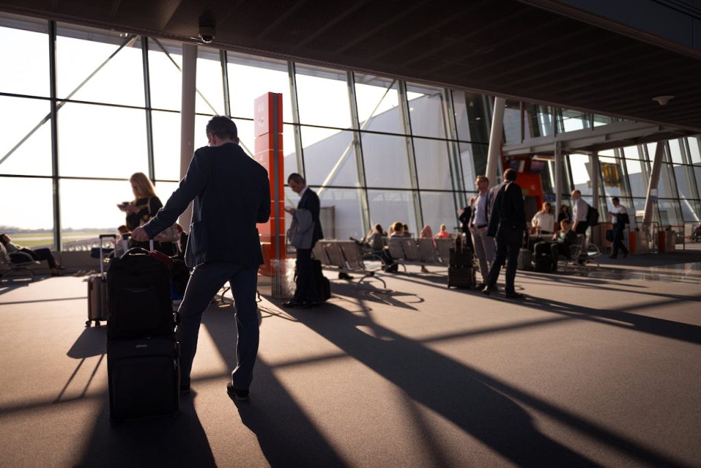 A wide shot of a busy U.S. airport terminal with people checking departure boards.