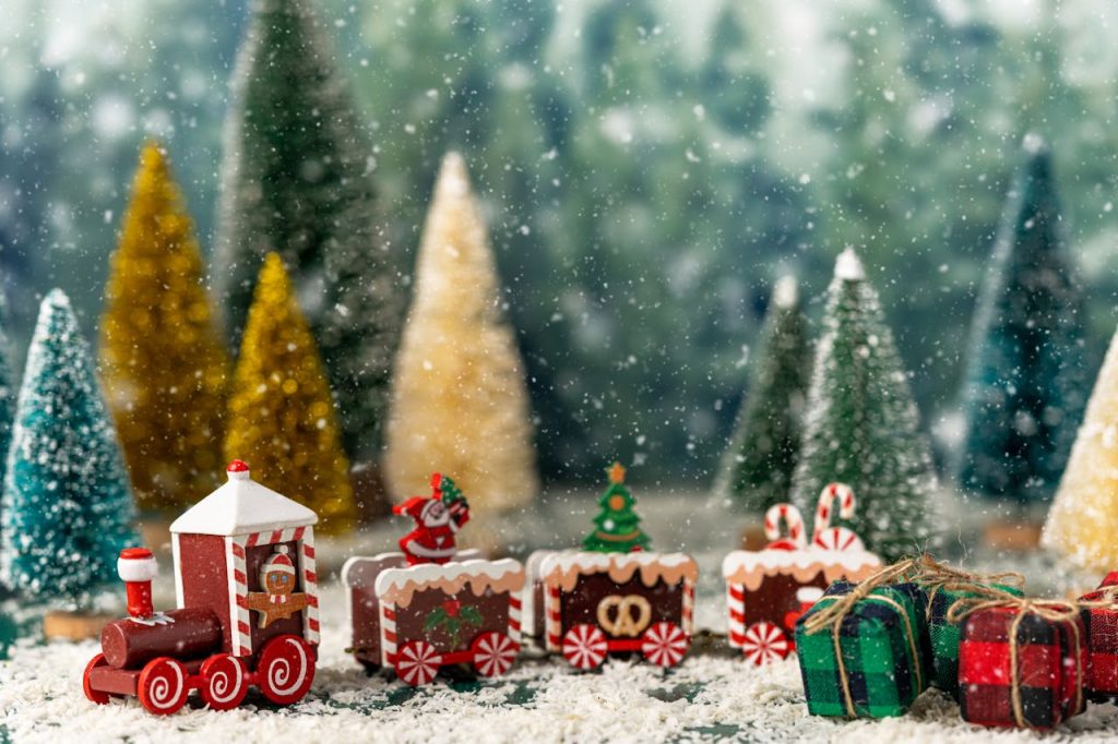 A train model on snowy tracks inside a decorated window.