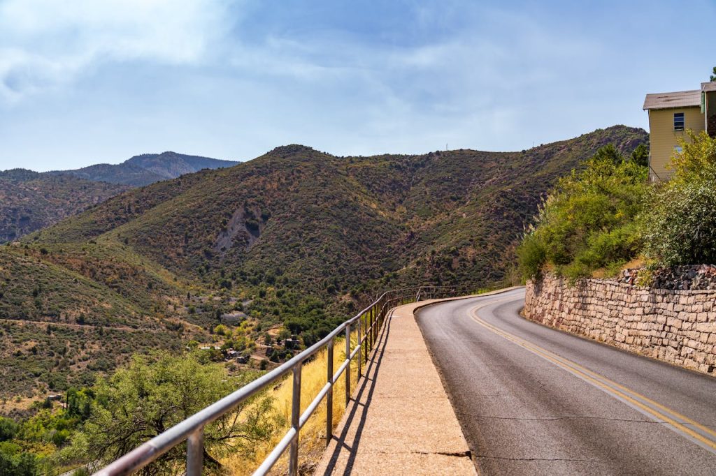 Gray Concrete Road Near Green Mountains Under Blue Sky
