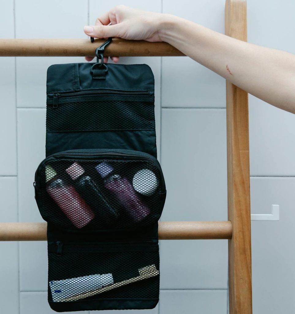 A compact toiletry bag opened on a bathroom counter with travel sized bottles arranged upright and visible.