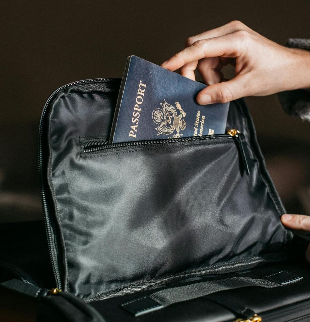 A close-up of a traveler placing a passport and travel documents into a secure pouch or hotel safe.