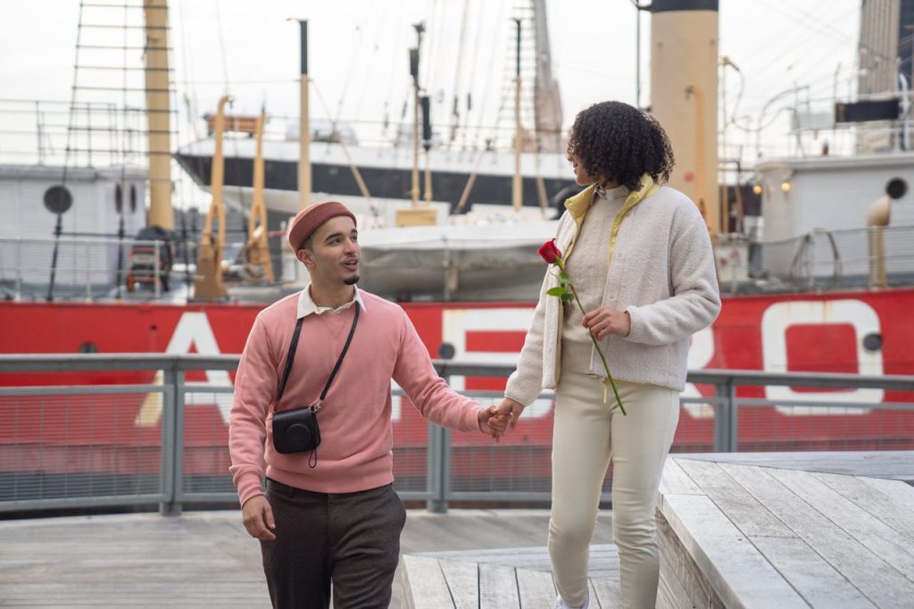 Ethnic couple holding hands and walking on city embankment