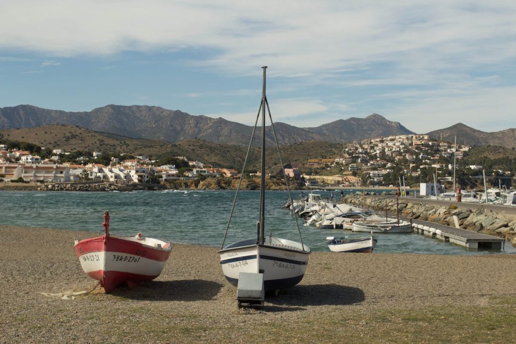 White Red and Black Sail Boat on Gray Sand Roses, Spain