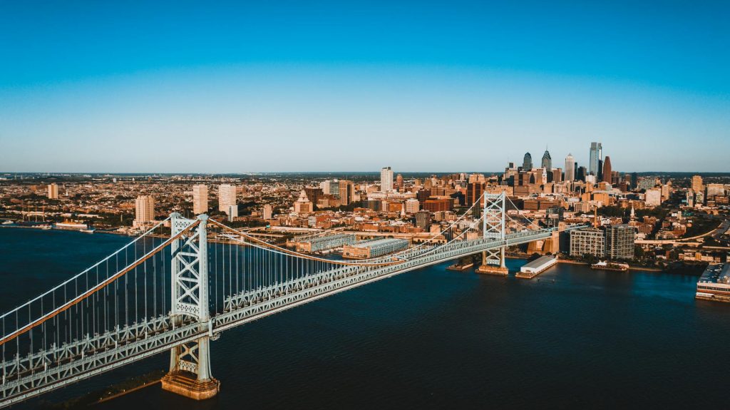 Modern bridge over river behind cityscape under sky