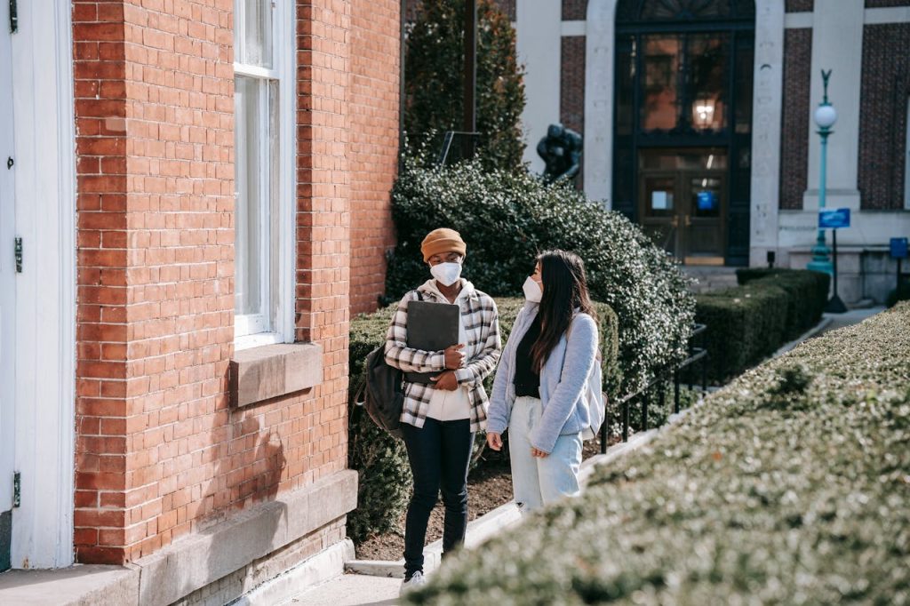 Multiracial female friends in masks strolling in street